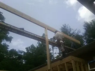 Carpenter setting a ridge beam over a new addition frame — Ice Dam Removal by Roofing Brothers in Pratt