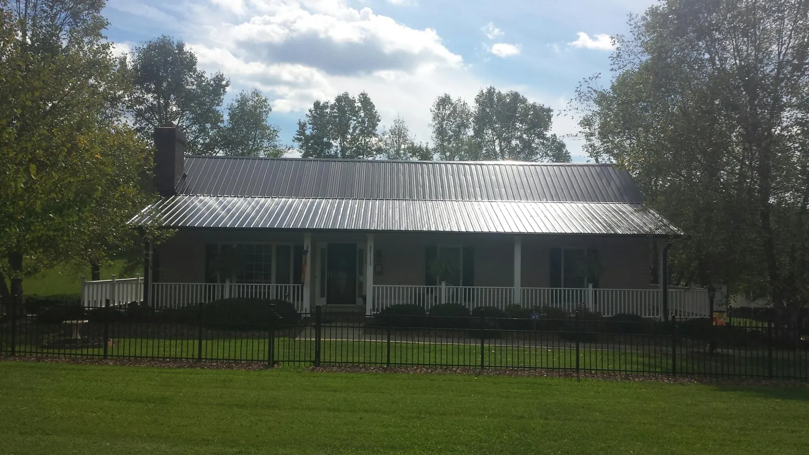 Gray metal roof on a brick ranch with a full width front porch — Gutter Guard Installation work by our crew in Pratt