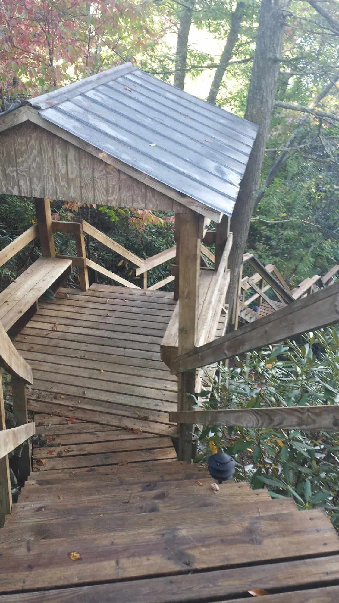 Metal roofed shelter over wooden steps on a wooded walkway — Skylight Repair & Installation work by our crew in Pratt
