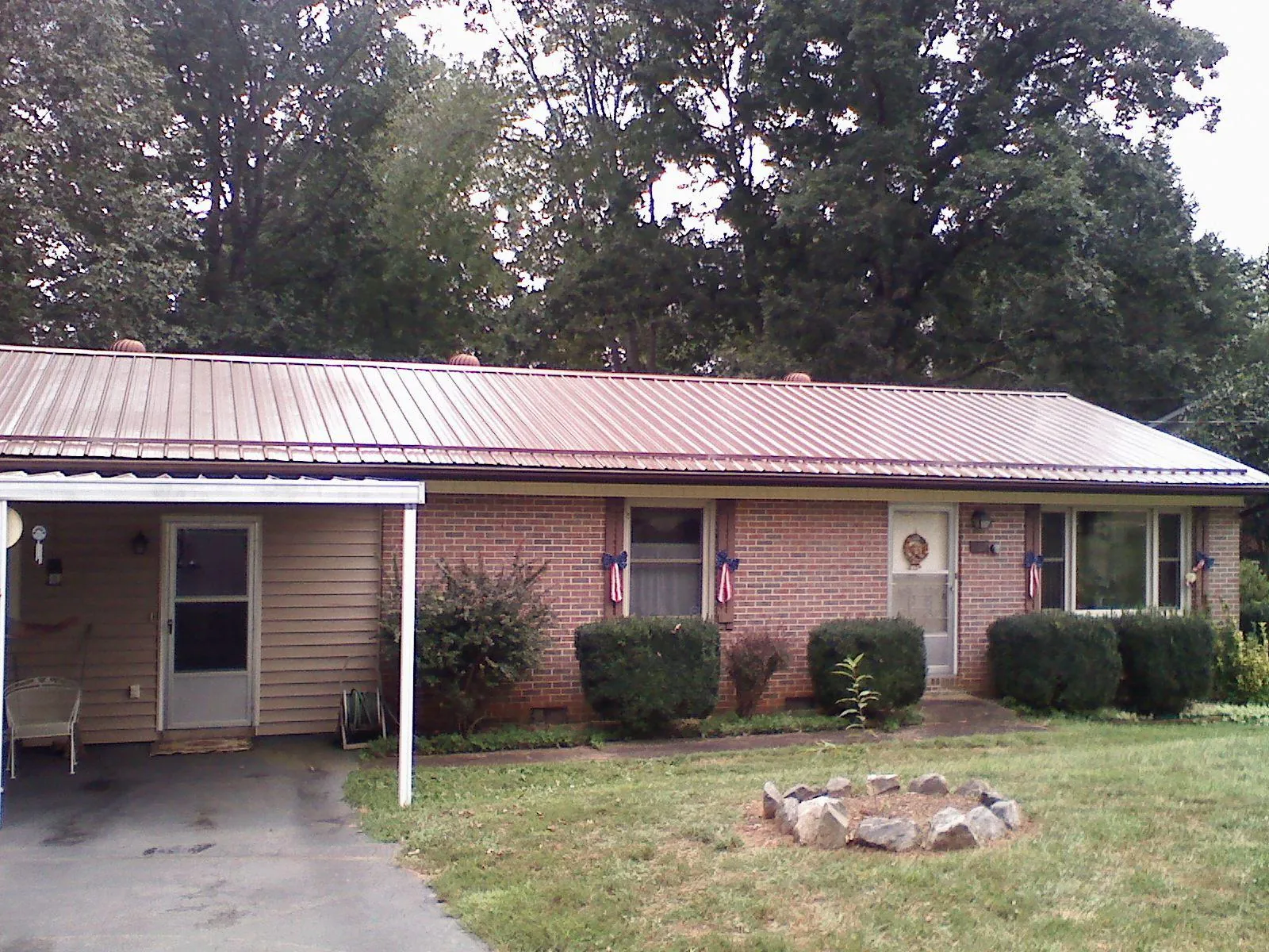 Bronze metal roof and carport on a brick ranch home — Roof Repair work by our crew in Pratt