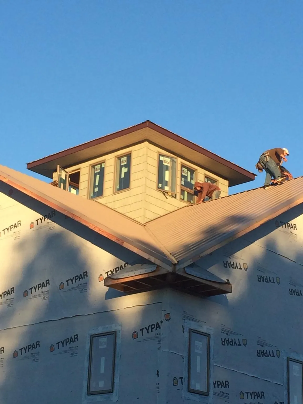 Roofers working around a rooftop cupola on a new metal roof at sunset — Roof Waterproofing in Pratt by Roofing Brothers